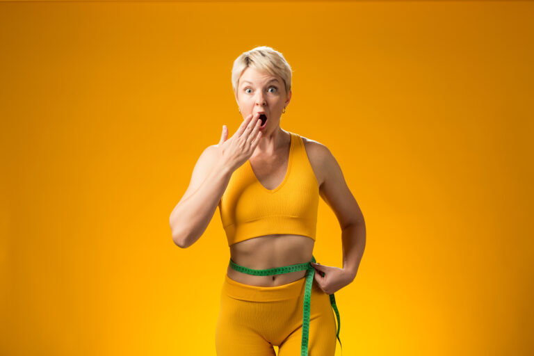 Fitness woman with measure tape isolated on yellow background. Weight loss and healthcare concept