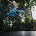 Little,Girl,Jumping,On,Trampoline,In,The,Backyard.,Dangers,And