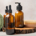 Bottles of dark amber glass with essential oil, massage brush and tropical leaves
