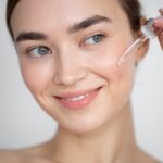 portrait-beautiful-woman-with-clear-skin-using-face-serum_23-2149207918