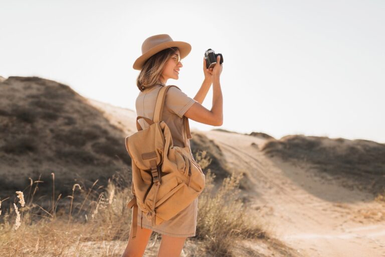 attractive-stylish-young-woman-khaki-dress-desert-traveling-africa-safari-wearing-hat-backpack-taking-photo-vintage-camera_285396-9174